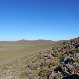 A rocky hillside above the wide, dry plain at Pali Aike