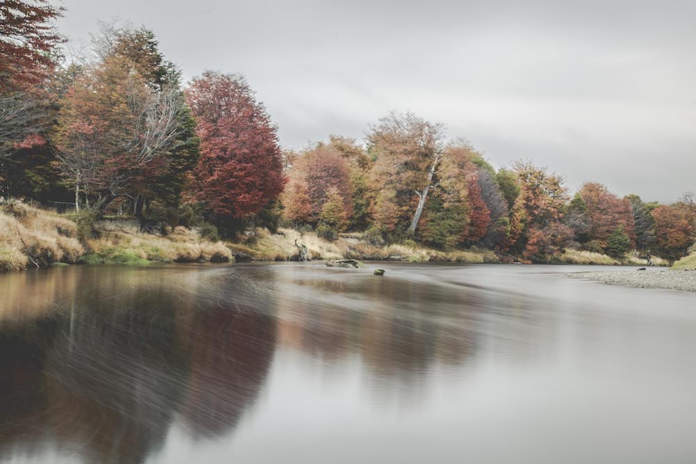 A river reflecting a forest of red and gold autumn foliage