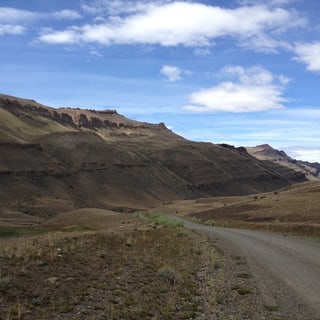A gravel road winding between the bare hills of Sierra Baguales