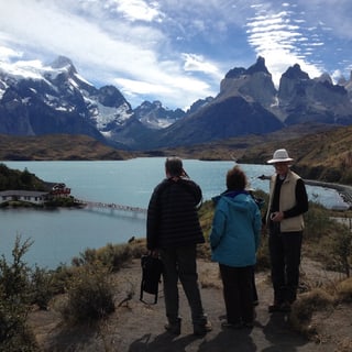 Three visitors looking across a lake toward the mountains of Torres del Paine