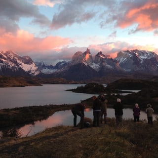 Visitors watching pink sunrise clouds over the lakes and mountains of Torres del Paine
