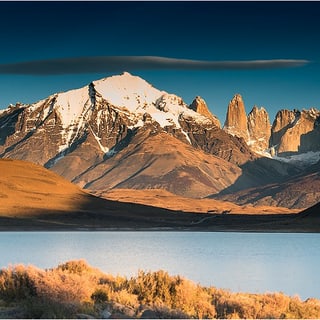 Golden grass and a blue lake below sunlit mountains in Torres del Paine National Park